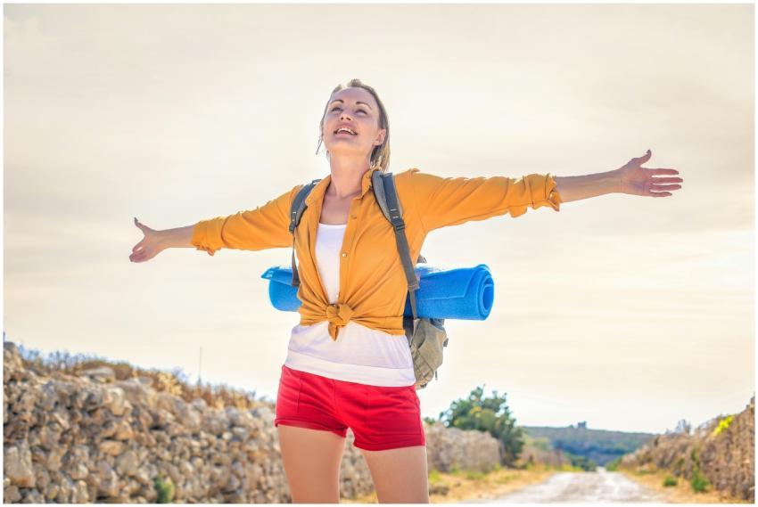Happy woman basking in sunlight on a summer hike w