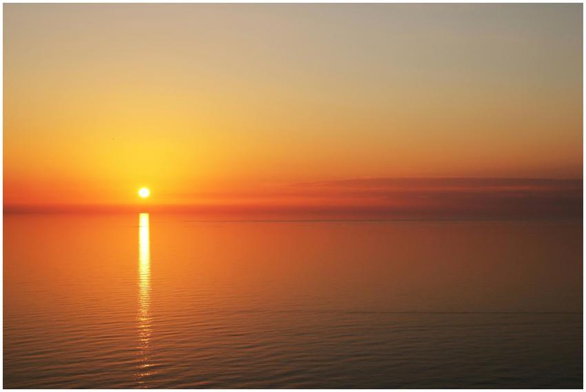 A tranquil sunset over calm ocean waters with gold