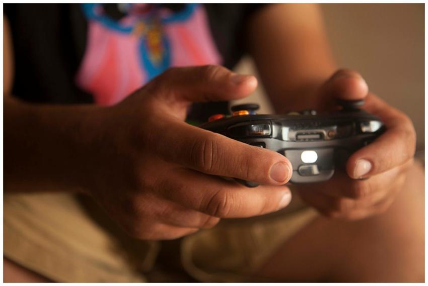 A person holding a wireless game controller indoor