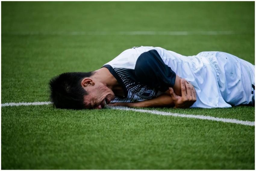 Soccer player lies on the field in pain during a g