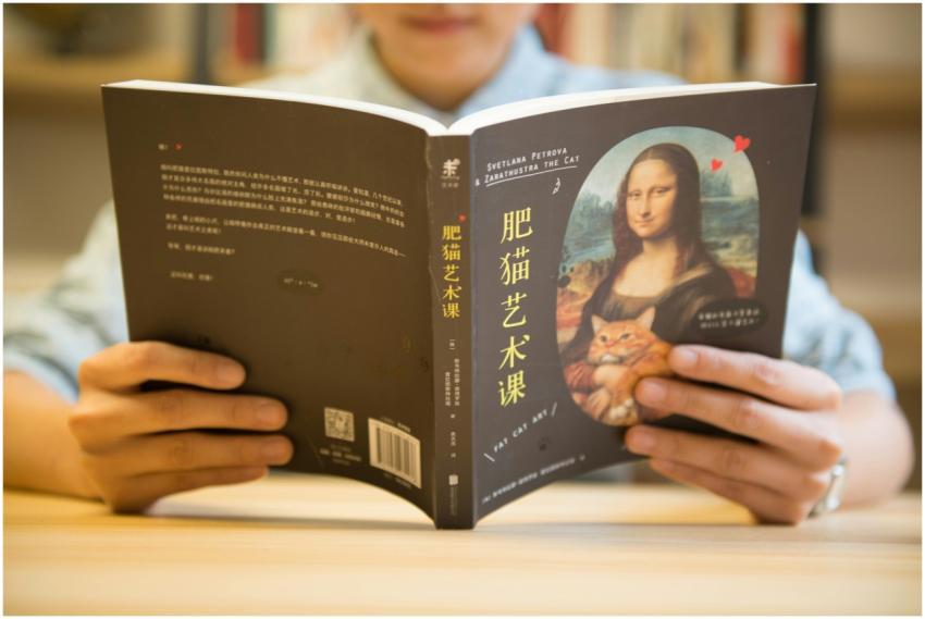 Person reading a book with 'Fat Cat Art' cover fea