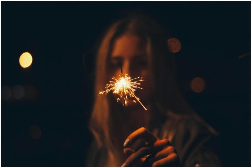 A blurred image of a woman holding a bright sparkl