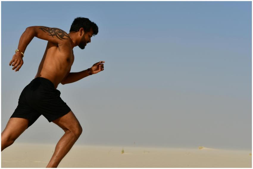 A muscular man sprinting shirtless through a deser