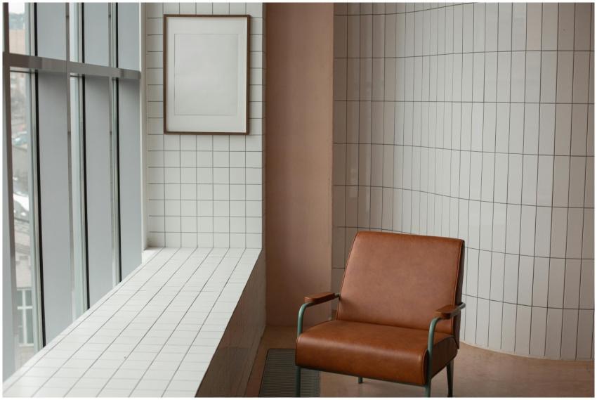 Brown armchair placed near mock up frame hanging n