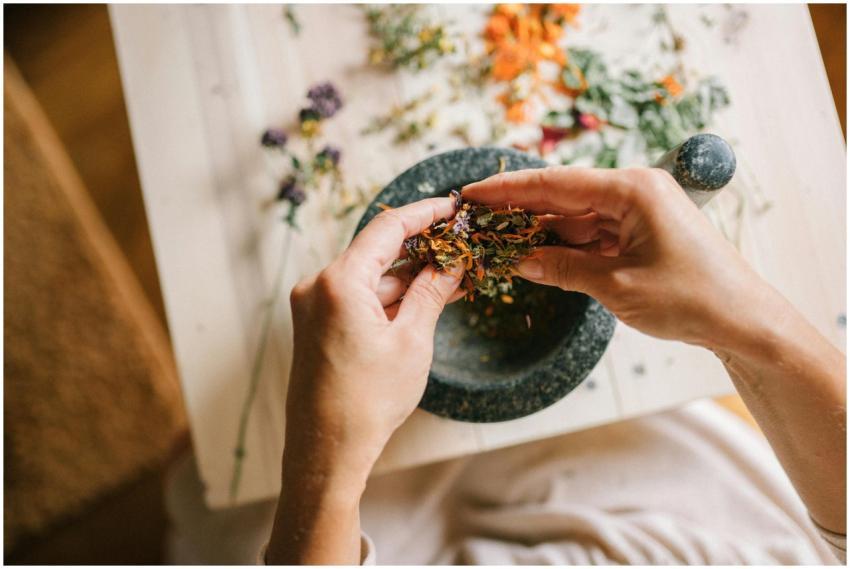 Close-up of hands mixing dried herbs with a mortar