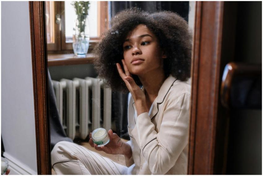 A woman applies skincare cream in a cozy home envi