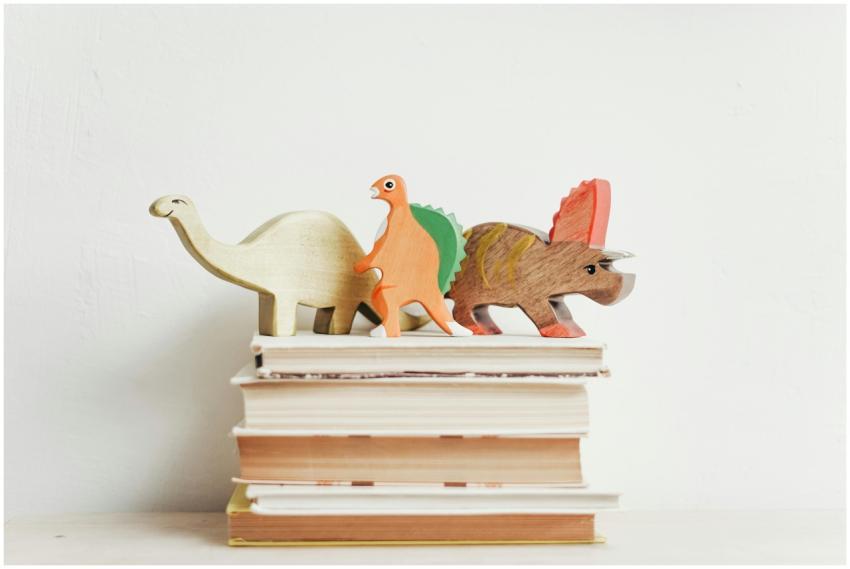 Colorful wooden dinosaurs on top of a stack of har