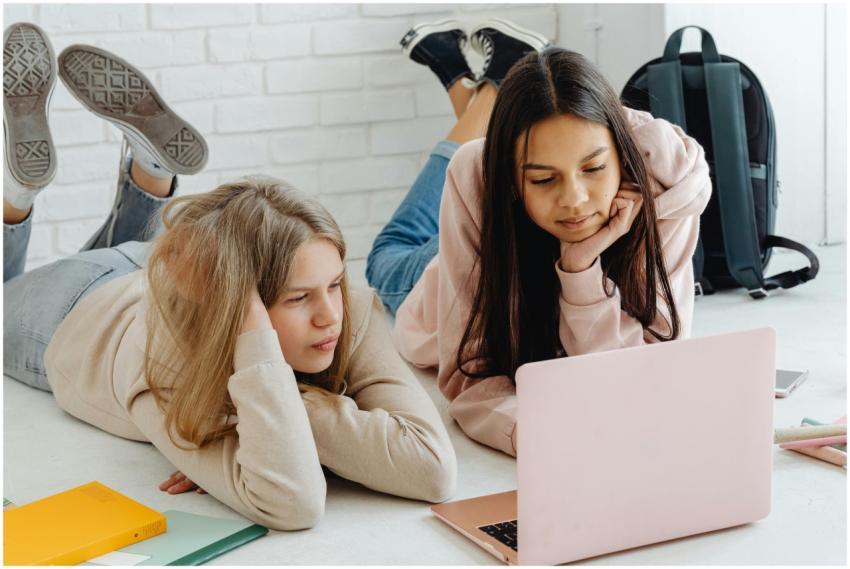 Two teenage girls studying together using a laptop