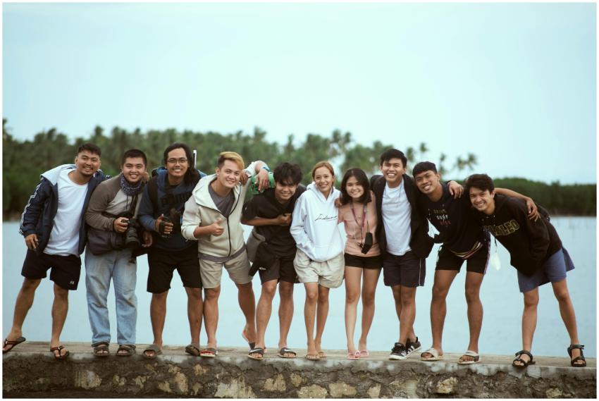 Cheerful group of friends posing by a lakeside, en