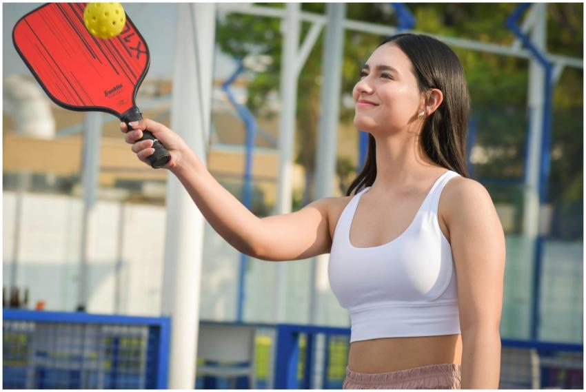 Young woman playing pickleball outdoors wearing sp