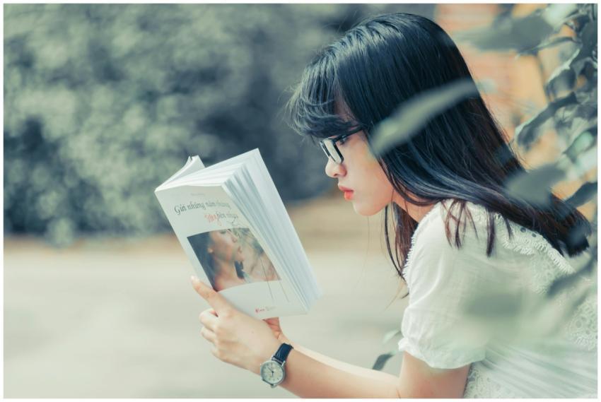 Asian woman reading a book in summer. Relaxed outd