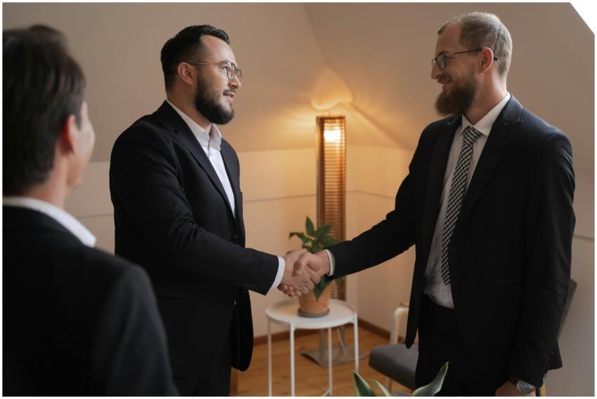 Two businessmen in suits shaking hands in a warm o