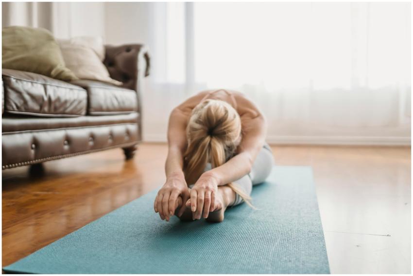 A woman performs a yoga stretch on a mat in a cozy