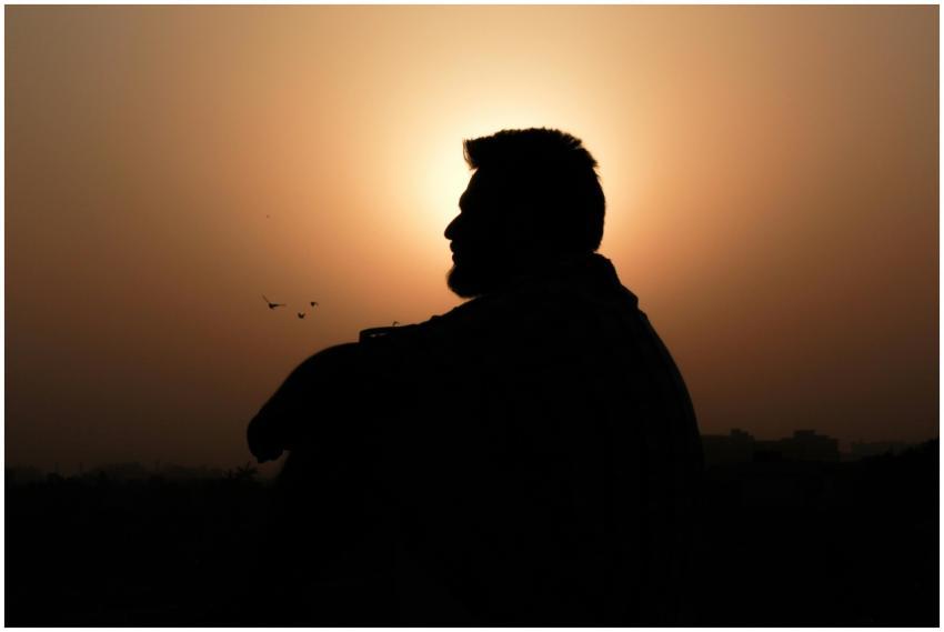 A silhouette of a man sitting in profile against a