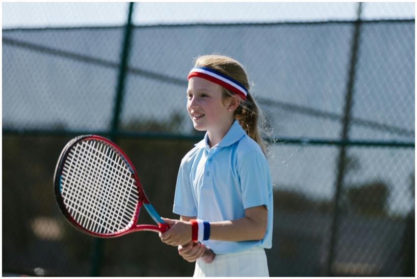 A young girl in athletic wear happily playing tenn