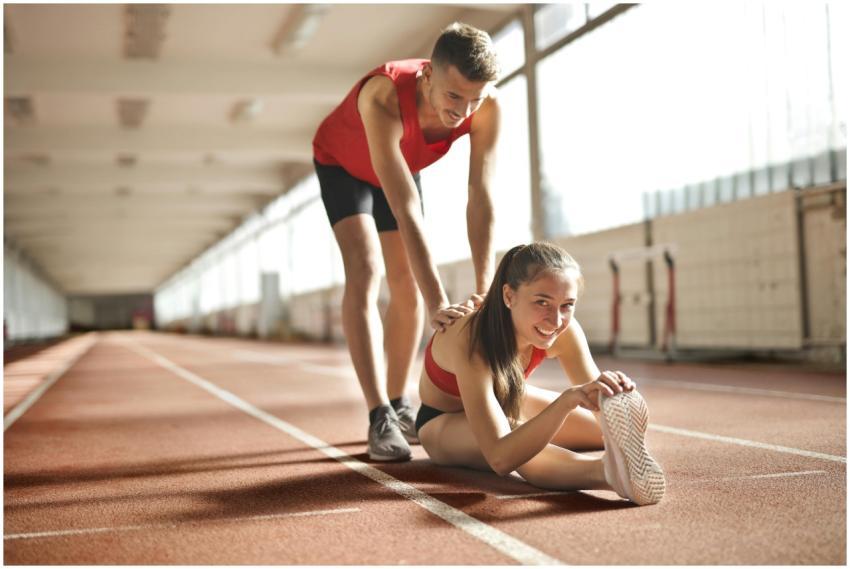 Two young athletes stretch together on an indoor t