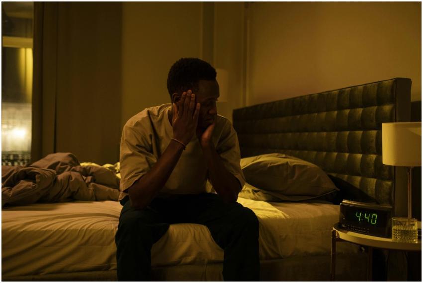 African American man sitting on a bed struggling w