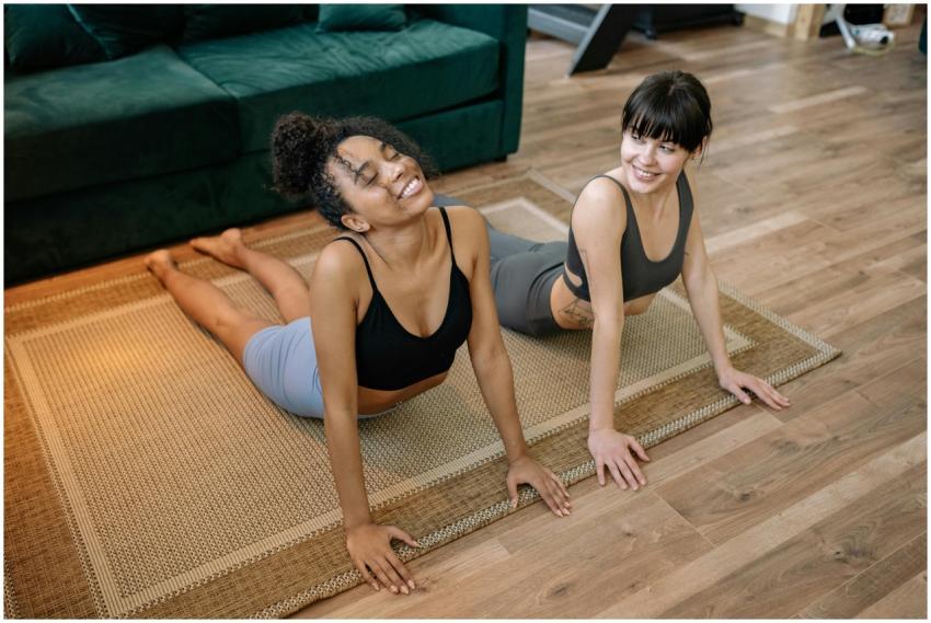 Two women smiling while performing yoga poses indo