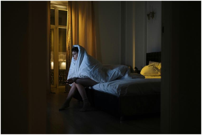Woman wrapped in blanket watching TV, battling ins