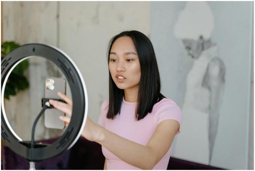 Young woman using a smartphone and ring light for