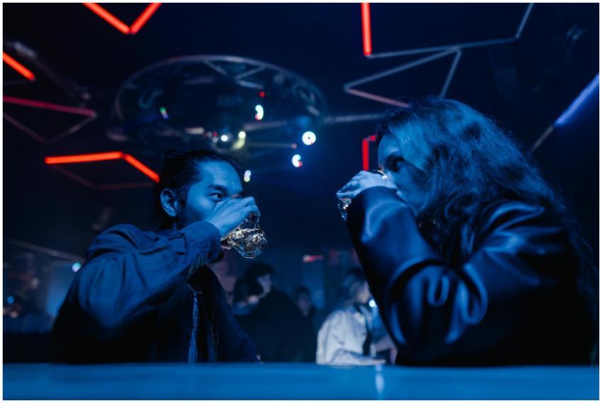Two friends enjoying drinks at a vibrant nightclub