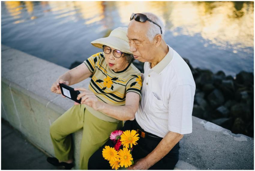 An elderly Asian couple takes a cheerful selfie by