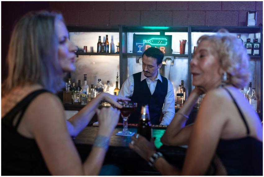 Two women enjoying drinks at a bar with a bartende