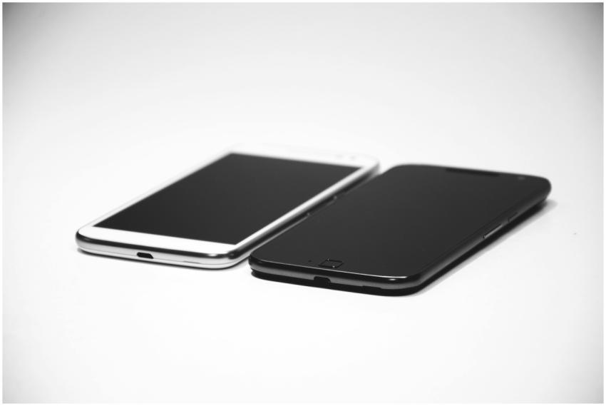 Two smartphones, one black and one white, placed o