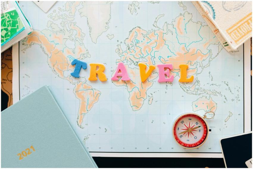 Flat lay of a map with colorful letters "TRAVEL" a