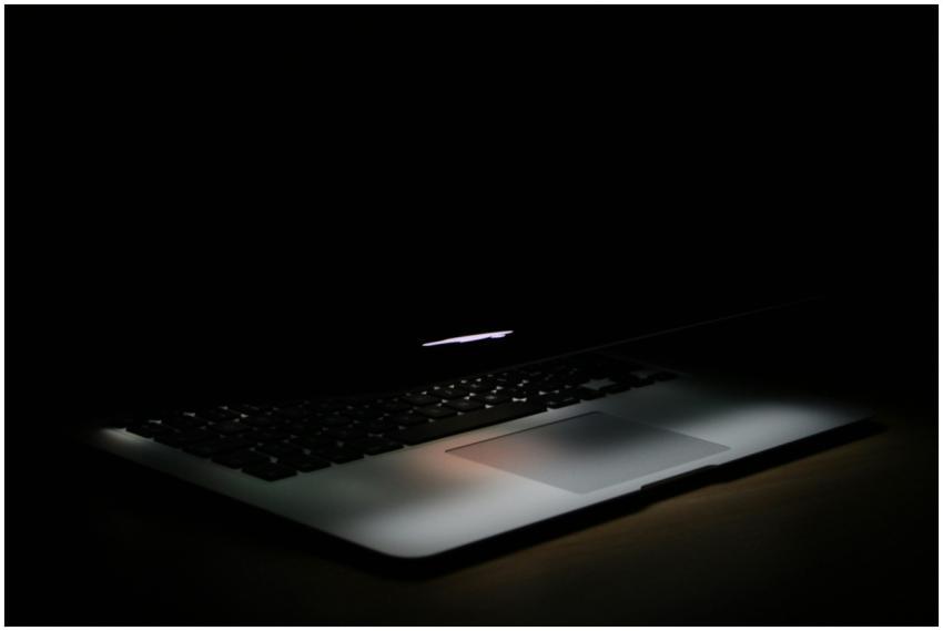 A sleek laptop with soft backlighting in a dark, m
