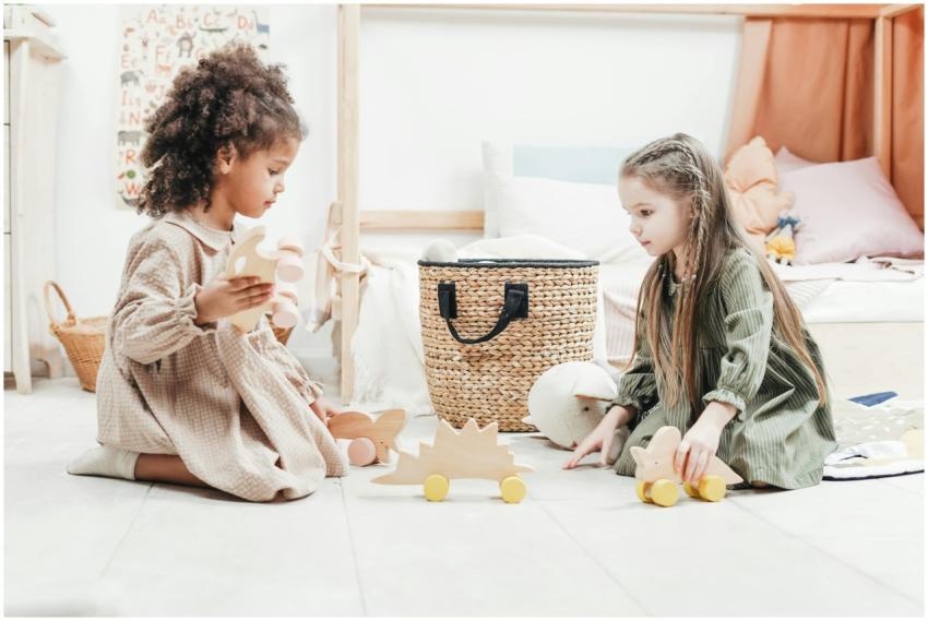 Two young girls enjoy playing with wooden toys in