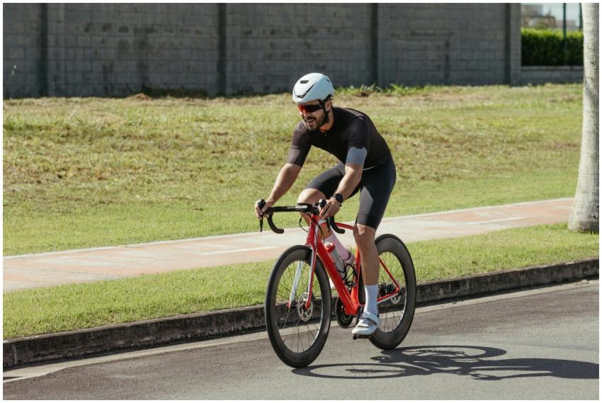 An adult male cyclist in gear riding a red bike on