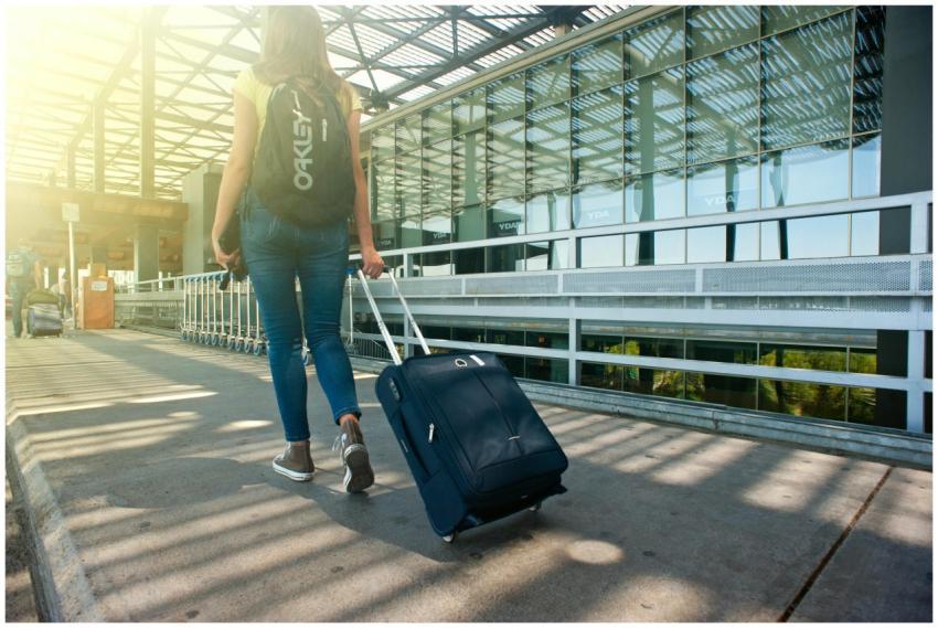 A woman walks with a suitcase outside an airport t