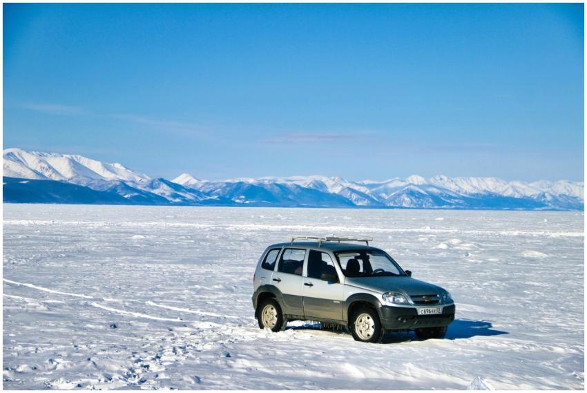 An SUV parked on a snowy expanse with majestic mou