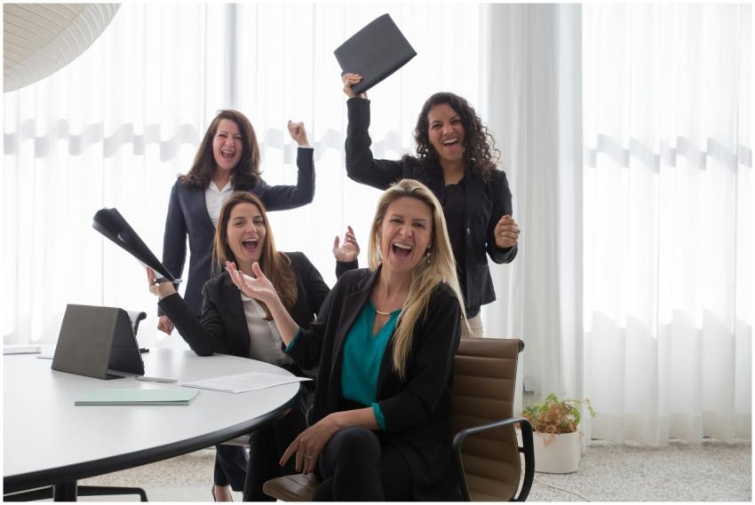 Four women in an office celebrating success and te
