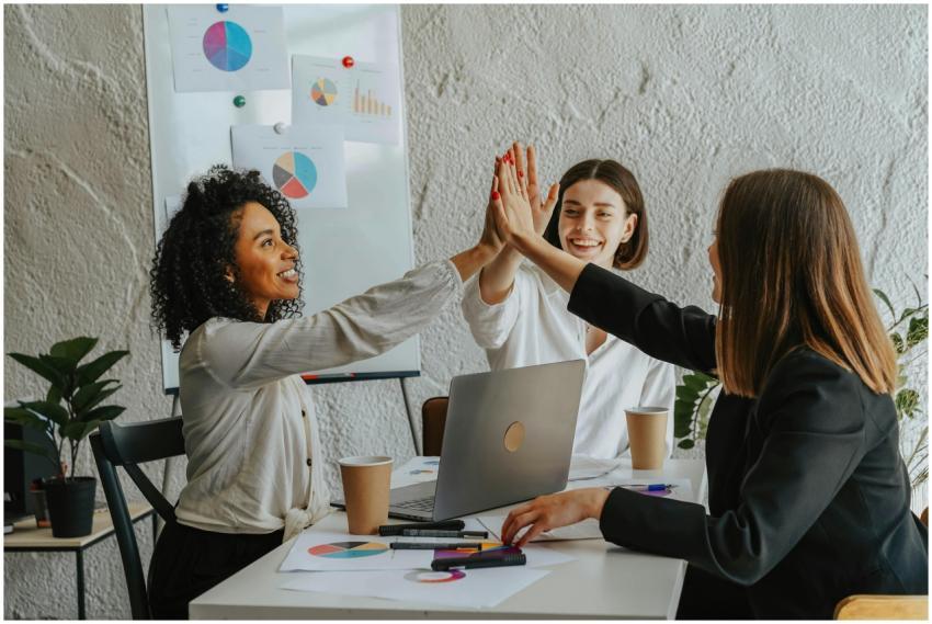 Three businesswomen in office having a high-five d