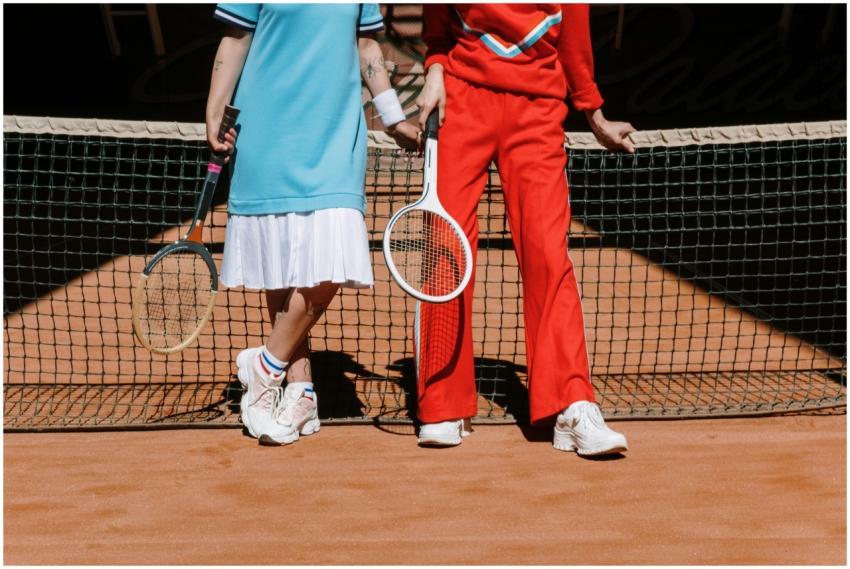 Two tennis players in sporty outfits standing at t