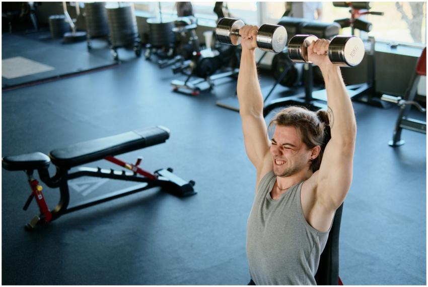 Man intensely lifting dumbbells in a modern gym, s