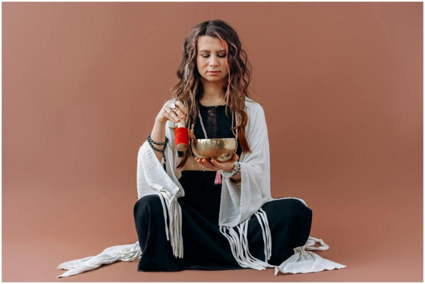 A serene woman meditates with a singing bowl, evok