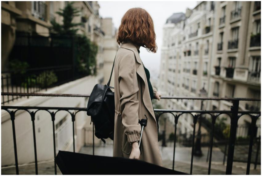 Woman in trench coat walking through a Parisian st