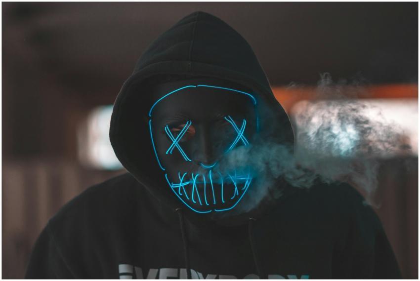 Hooded figure with a neon mask emitting smoke, cre