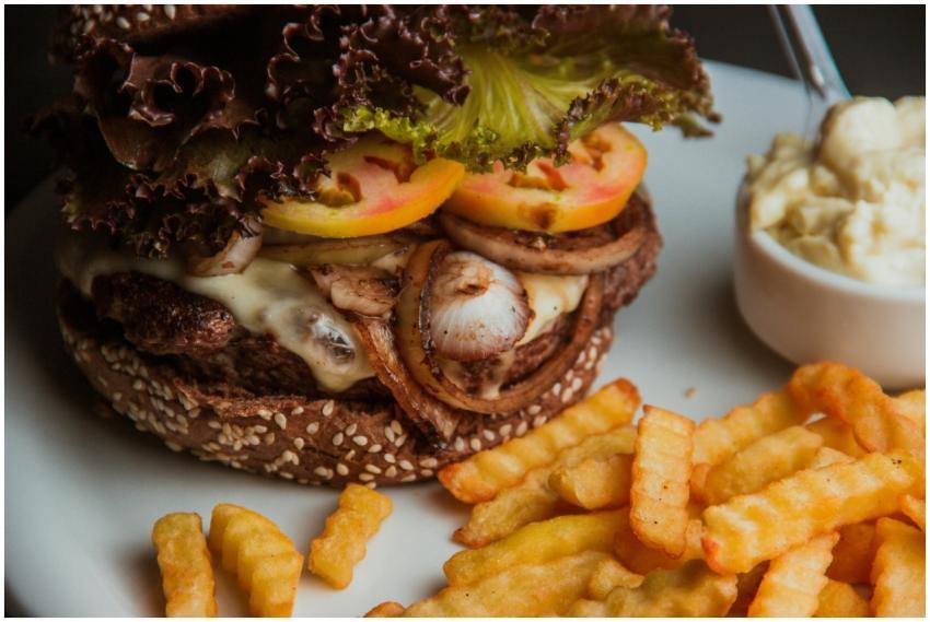 Close-up of a juicy cheeseburger with fries and a