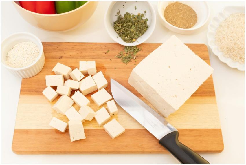 Sliced tofu on cutting board with herbs and spices