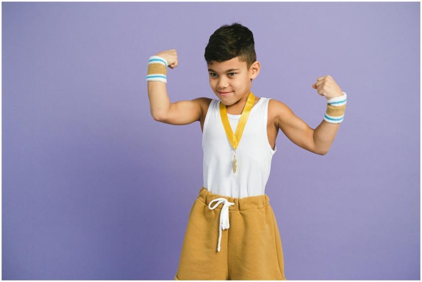 Young boy confidently flexes muscles with medal an