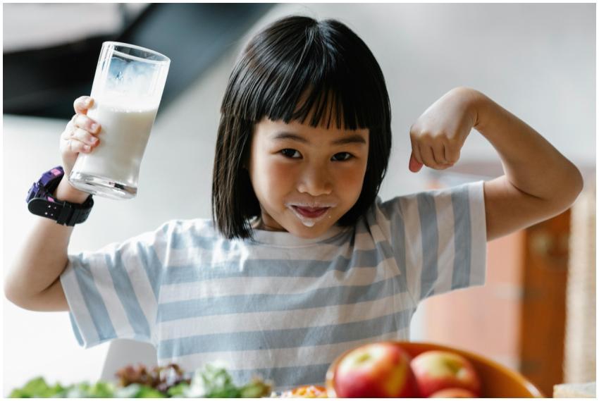 A happy child drinking milk and flexing muscles, p