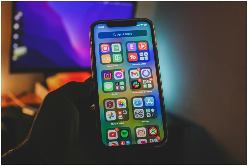 A hand holds a smartphone showing a colorful app-f