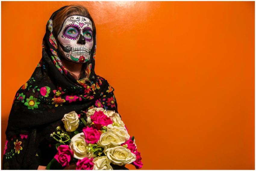 A woman with face paint and floral scarf celebrate