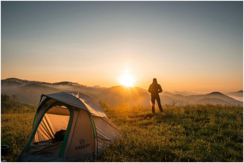 A camper enjoys the sunrise in a mountain setting