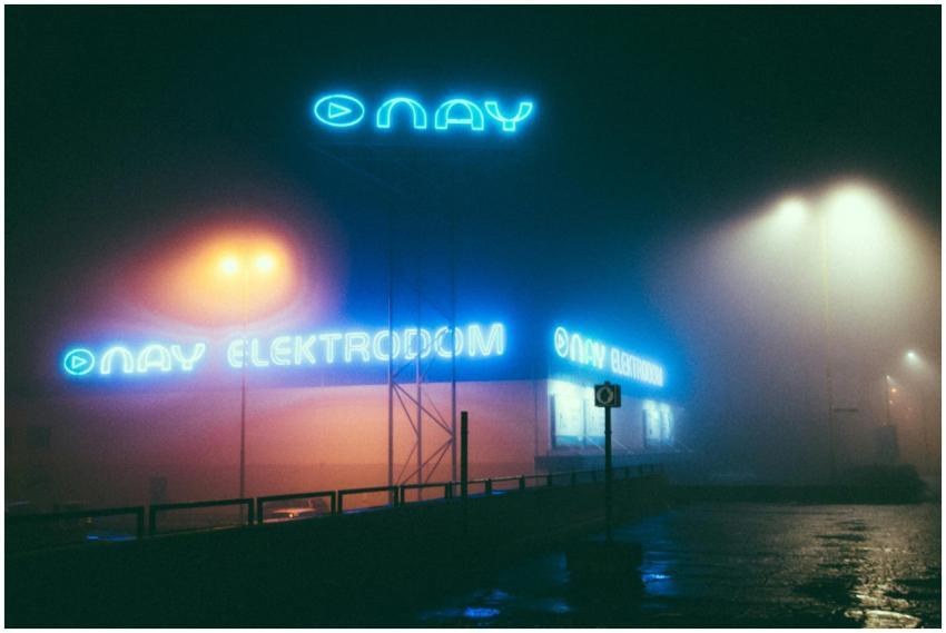 Foggy night street scene featuring neon lights and