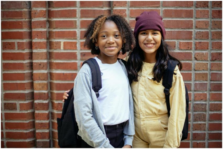 Two diverse teenagers happily posing with backpack